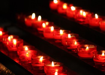 lit votive candles with a warm red glow, the blood of the Christian martyrs